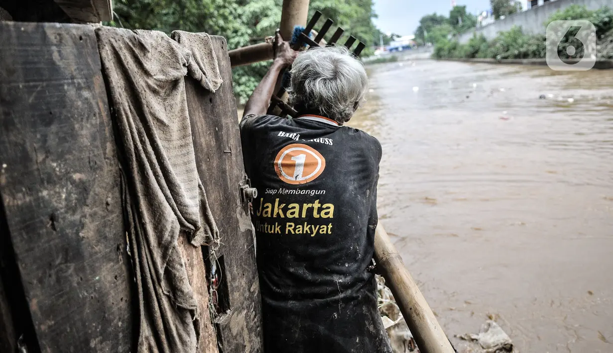 Warga berdiri di belakang rumah yang bersebelahan dengan Kali Ciliwung di permukiman Kebon Pala, Jatinegara, Jakarta, Minggu (25/10/2020). Tidak adanya tanggul antara permukiman dan Kali Ciliwung menyebabkan banjir yang meluap sejak dini hari tadi lambat surut. (merdeka.com/Iqbal Nugroho)