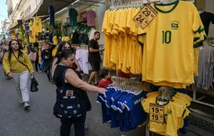 Seorang penggemar sepak bola Brasil melihat-lihat jersey tim nasional sepak bola yang dipajang di pasar Saara, Rio de Janeiro, Brasil, pada Selasa 9 Juni 2026, menjelang turnamen Piala Dunia FIFA 2026. (Nelson ALMEIDA/AFP)