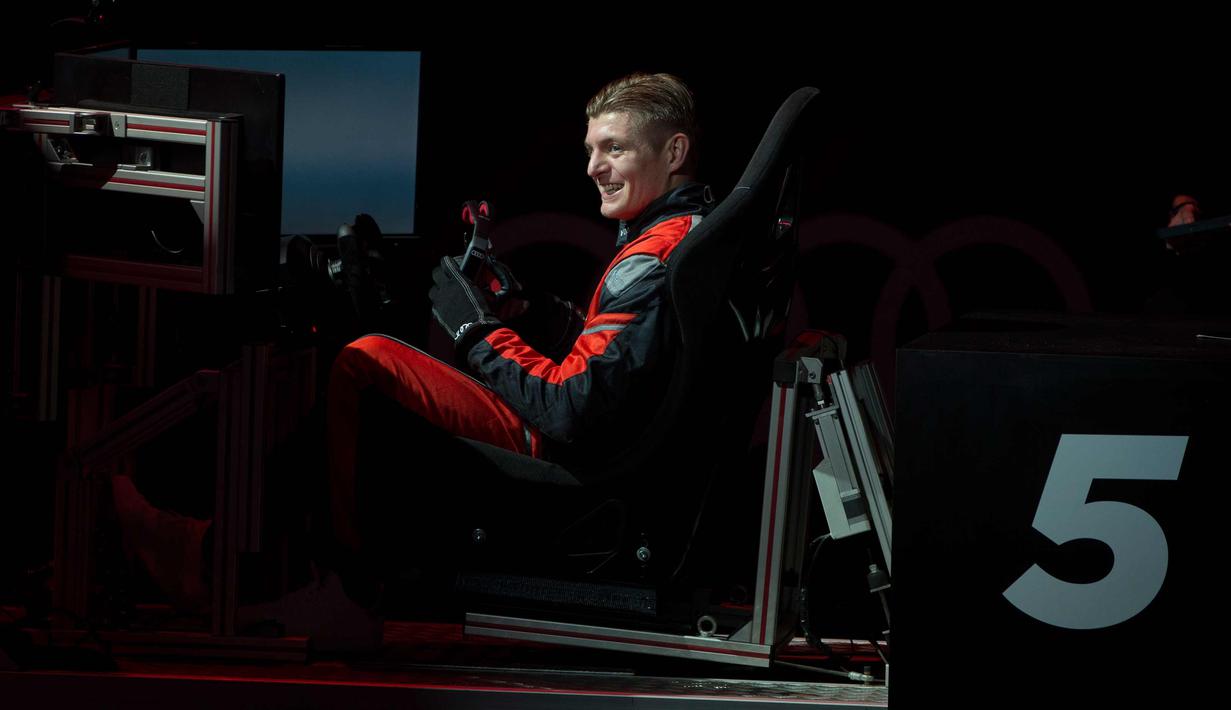 Gelandang Real Madrid, Toni Kroos tersenyum setelah menyelesaikan balapan di simulator Formula E selama sebuah acara promosi di Madrid, Spanyol, (23/11). (AP Photo / Paul White)