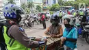 Petugas kepolisian lalu lintas mengecek SIM pengendara motor saat Operasi Zebra Jaya 2020 di kawasan Cawang, Jakarta, Senin (26/10/2020). Operasi Zebra Jaya dilaksanakan pada 26 Oktober-8 November 2020 untuk menekan jumlah pelanggaran lalu lintas. (Liputan6.com/Faizal Fanani)
