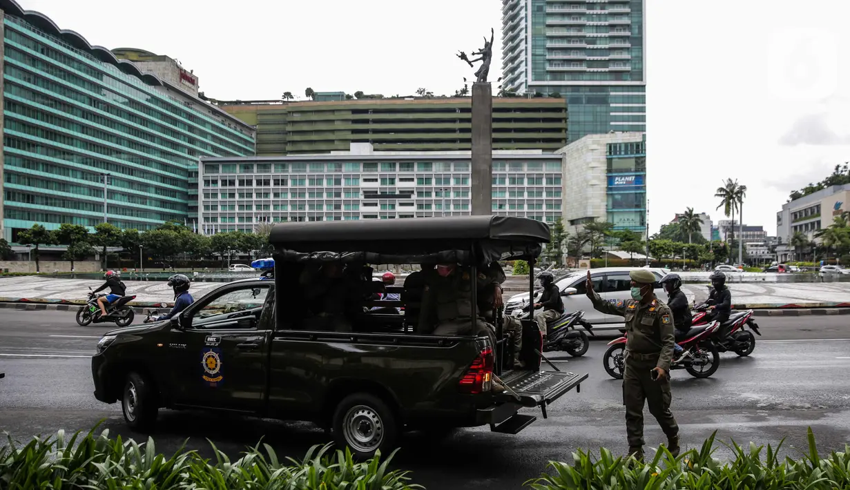 Petugas Satpol PP melakukan sosialisasi kepada masyarakat guna mencegah penularan Covid-19 di Bundaran HI, Jakarta, Kamis (19/3/2020). Sosialisasi yang mengajak masyarakat untuk menerapkan PHBS untuk mengantisipasi penyebaran Covid-19. (Liputan6.com/Faizal Fanani)