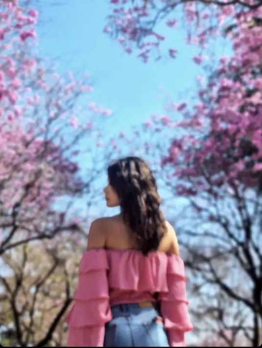 Callista tampil seru dalam OOTD liburannya. Selain pakai kaus cropped top hitam dan celana panjang hitam, ia juga tampil girly dengan blouse off-the-shoulder warna pink dan celana jeans. Menyatu dengan keindahan pohon sakura. [Foto: Instagram @callistaarum]