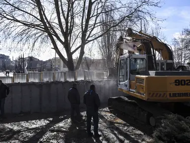 Kendaraan alat berat meruntuhkan tembok kontroversial di Mitrovica, Kosovo, Minggu (5/2). Tembok tersebut telah memicu ketegangan antara Kosovo dan negara tetangga Serbia. (AFP PHOTO/ ARMEND NIMANI)