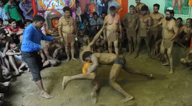 Seorang pegulat berusaha membanting lawannya pada pertandingan gulat tradisional di festival Nag Panchami di Allahabad, India, (7/8). Festival ini diadakan selama musim hujan dengan doa dan upeti untuk ular. (AFP PHOTO/SANJAY Kanojia)