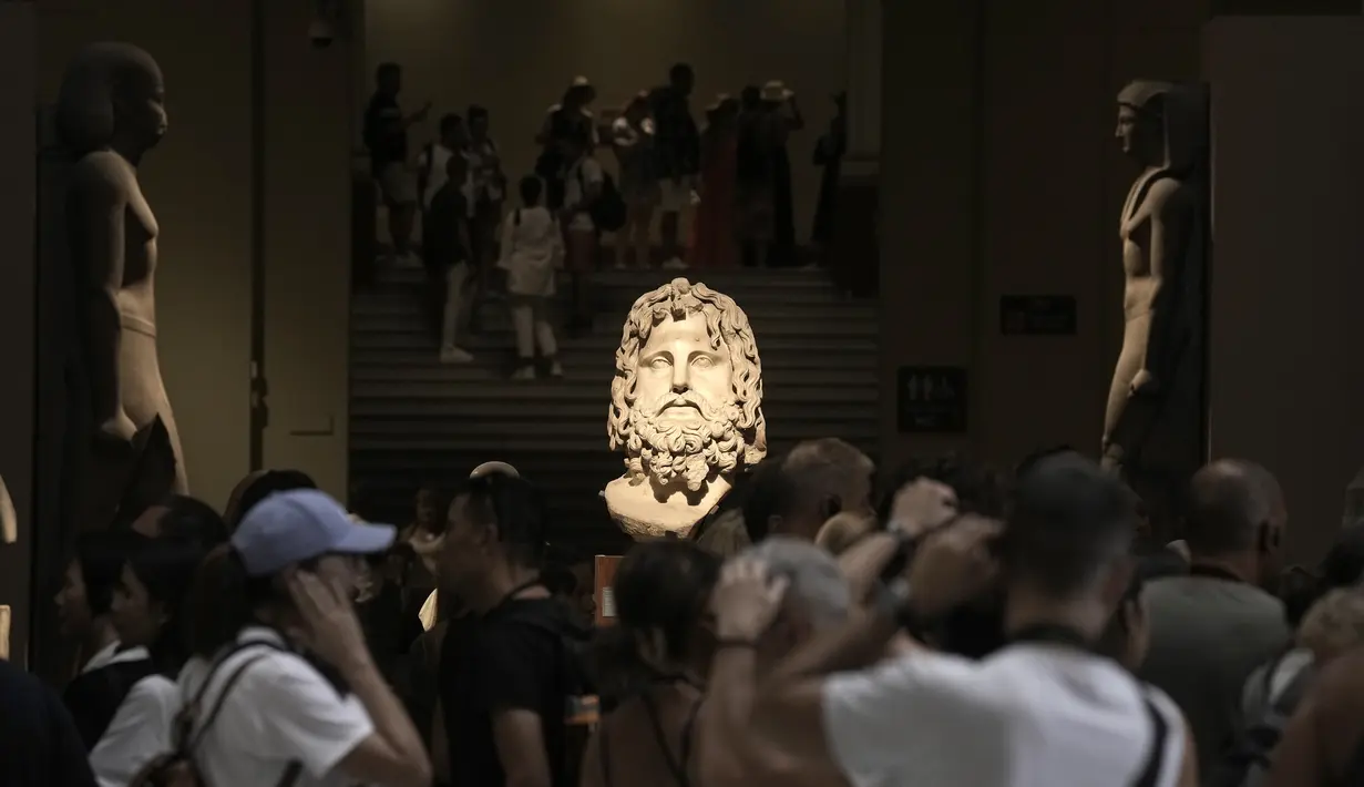 Ratusan turis mengelilingi kepala kolosal dewa Serapis, tengah, salah satu dewa terpenting pada periode Yunani dan Romawi, di museum Mesir di Kairo, Mesir, Rabu, 27 September 2023. (AP Photo/Amr Nabil)