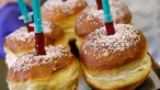 Pekerja berpose sambil membawa berliner (donat Jerman) dengan jarum suntik penuh raspberry jelly di toko roti Kreyenbuhl di Muri, Swiss pada 5 Februari 2021. Merespons hadirnya vaksin Covid-19, toko roti Kreyenbuhl mencoba merayakannya dengan membuat "Vaccine Berliners". (STEFAN WERMUTH/AFP)