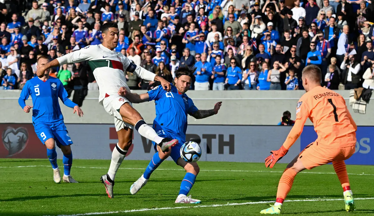 Pemain Timnas Portugal, Cristiano Ronaldo (kiri), berusaha menjebol gawang Timnas Islandia yang dijaga oleh Runar Runarsson dalam pertandingan lanjutan grup J Kualifikasi Euro 2024 yang berlangsung di Laugardalsvollur, Reykjavik, Rabu (21/6/2023) dini hari WIB. Pertandingan ini merupakan penampilan CR7 yang ke-200 bersama Portugal. (AFP/Halldor Kolbeins)