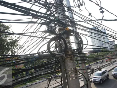 Instalasi kabel saling bersinggungan di tiang Jalan Gunung Sahari, Jakarta, Rabu (13/7). Kurangnya penataan membuat instalasi kabel di Ibu Kota terlihat semrawut dan mengganggu pemandangan. (Liputan6.com/Immanuel Antonius)