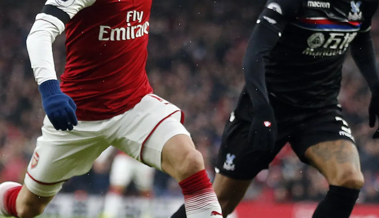 Pemain Arsenal, Mesut Ozil (kiri) berusaha melewati adangan pemain Crystal Palace, Patrick van Aanholt pada lanjutan Premier League di Emirates stadium, London, (20/1/2018). Arsenal menang 4-1. (AP/Frank Augstein)