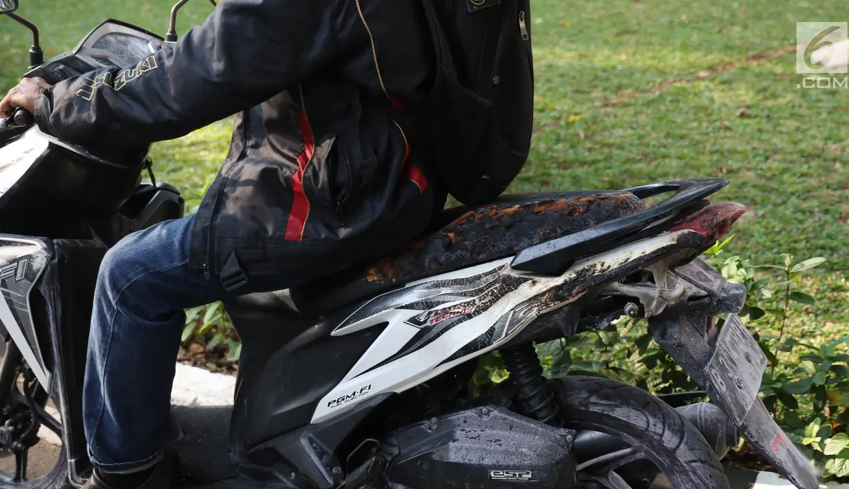 Pengendara membawa sepeda motor Vario yang terkena ledakan salah motor Yamaha Mio Soul GT di parkiran Kemlu, Jakarta, Rabu (7/8/2019). Ledakan motor yang diduga akibat korsleting listrik berdampak beberapa motor ikut terbakar. (Liputan6.com/Angga Yuniar)