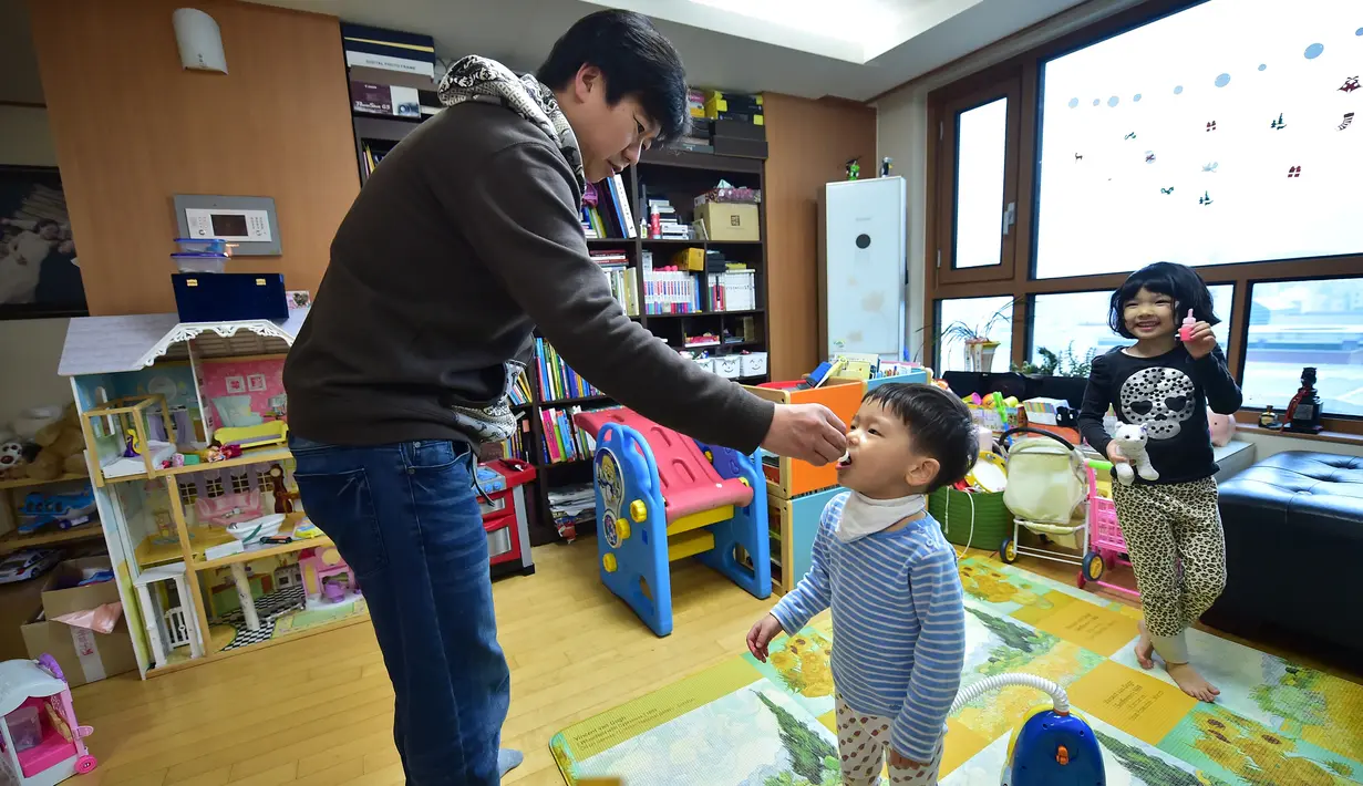 Kim Jin-Sung memberikan obat dingin untuk anaknya Won-Woo di apartemen mereka di Seoul. Sebuah ide yang tak biasa dimana anak sehari-hari dapat diurus oleh seorang pria yang merupakan tanggung jawab wanita. (AFP PHOTO/JU)