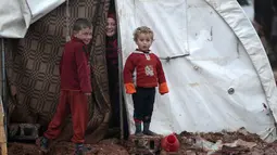 Tiga bocah pengungsi Suriah berdiri di depan tenda yang ada di kamp pengungsi Bab Al-Salam, dekat perbatasan Suriah-Turki, Provinsi Aleppo Utara, Senin (26/12). Di sini tercatat sekitar ribuan warga yang telah lama hidup di tenda. (REUTERS/Khalil Ashawi)