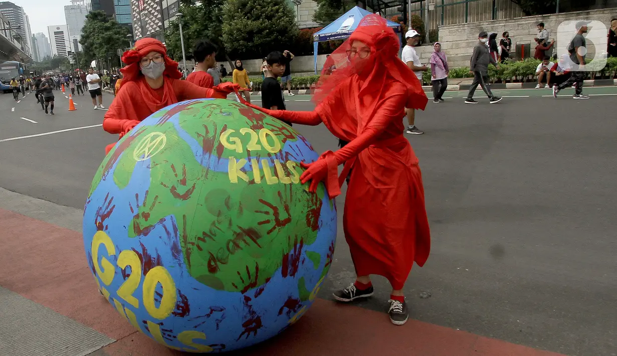 Aktivis lingkungan dari Extinction Rebellion Indonesia melakukan aksi penanganan mitigasi krisis iklim di Bundaran HI, Jakarta, Minggu (13/11/2022). Aktivis menuntut kepedulian negara-negara peserta KTT G20 untuk melakukan transisi energi yang berkelanjutan dan berkeadilan dalam krisis iklim. (merdeka.com/Arie Basuki)