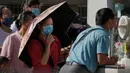 Warga yang memakai masker menyaksikan seorang pria melakukan swab tenggorokan rutin COVID-19 di tempat pengujian virus corona di Beijing, Selasa (6/9/2022).  Swab test dilakukan untuk mengetahui apakah seseorang terpapar virus COVID-19. (AP Photo/Andy Wong)
