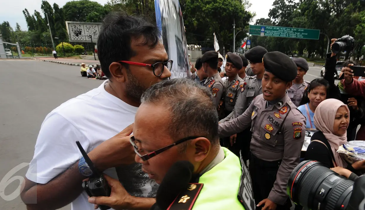 Polisi berusaha menahan aktivis KontraS saat akan masuk kawasan Sekretariat Negara untuk menyampaikan Kartu Pos Desak Presiden Selesaikan Kasus Munir, Jakarta, Selasa (17/1). Kartu dikumpulkan dari 20 kota di Indonesia. (Liputan6.com/Helmi Fithriansyah)