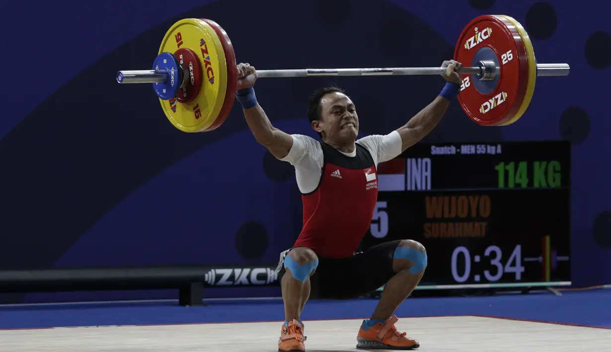 Lifter Suratman melakukan angkatan saat SEA Games 2019 cabang angkat besi nomor 55 kg di Stadion Rizal Memorial, Manila, Minggu (1/12). Dirinya meraih perak dengan total angkatan 250 kg. (Bola.com/M Iqbal Ichsan)