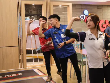 Dartslive Support Player asal Singapura Hedy Wong (kanan) dan Phuay Wei (tengah) bermain dengan pemain darts Indonesia Tirta Suparjo dalam acara peluncuran Darts Station di lantai F7 FX Sudirman, Senayan, Jakarta pada Sabtu (15/11/2025). (Bola.com/Abdul Aziz)