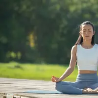 Seorang perempuan sedang melakukan meditasi di outdoor (Foto Dok: Freepik/jcomp).