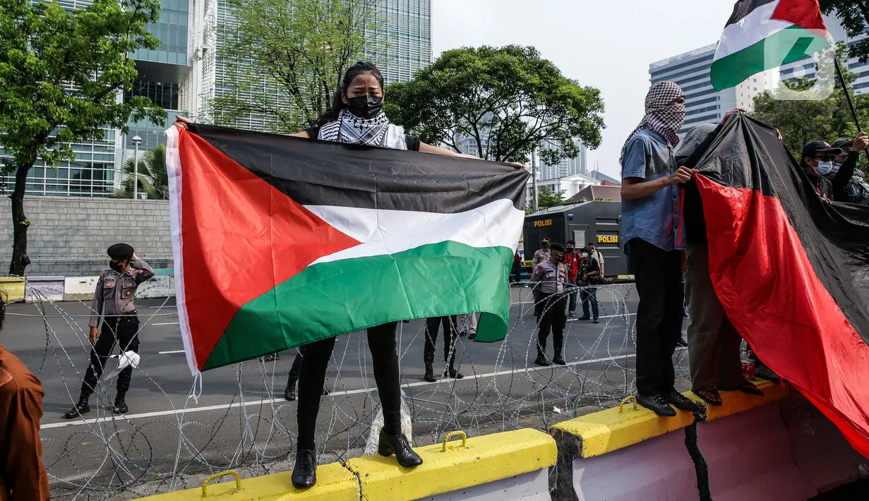 Pengunjuk rasa membentangkan bendera Palestina di depan Kedubes Amerika Serikat, Jumat (21/5/2021). Aksi yang diikuti berbagai elemen masyarakat dan ormas itu mengutuk serangan Israel dan mengajak masyarakat Indonesia untuk mendukung dan membantu Palestina. (Liputan6.com/Faizal Fanani)