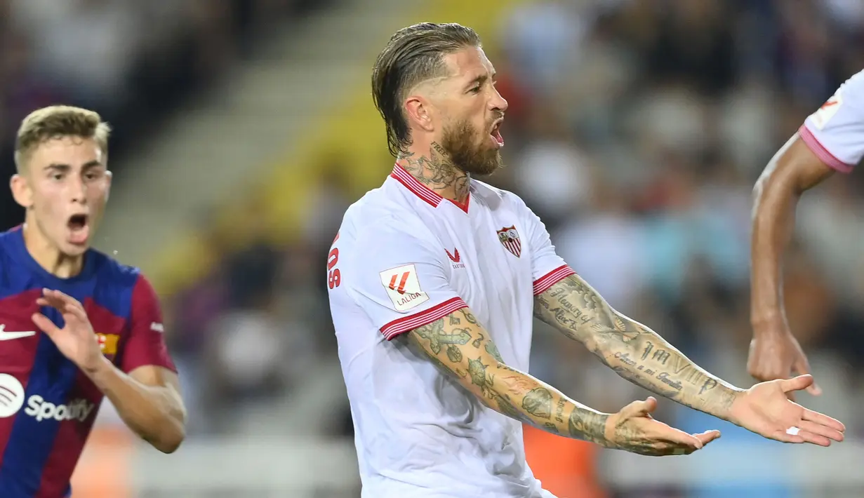 Reaksi pemain Sevilla, Sergio Ramos saat mencetak gol bunuh diri pada laga lanjutan Liga Spanyol 2023/2024 melawan Barcelona di Estadi Olimpic Lluis Companys, Barcelona, Spanyol, Sabtu (30/09/2023) dini hari WIB. Ramos yang berlari untuk menjaga pemain Barcelona lain malah salah mengantisipasi bola yang berujung masuk ke gawang timnya sendiri. (AFP/Pau Barrena)