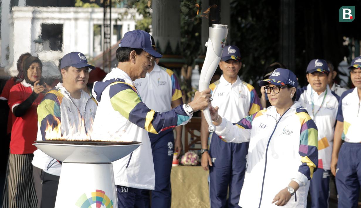Gubernur DIY Sri Sultan Hamengku Buwono X memberikan api obor kepada Menlu RI, Retno Marsudi, di Pagelaran Keraton Yogyakarta, Kamis (19/7/2018). Total jarak kirab Obor di Yogya ini sepanjang 11,5 kilometer. (Bola.com/M Iqbal Ichsan)