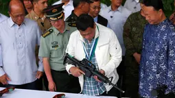 Presiden Filipina Rodrigo Duterte memeriksa senapan serbu CQA5 buatan China di Clark Airbase di Filipina (28/6). (AP Photo/Bullit Marquez)