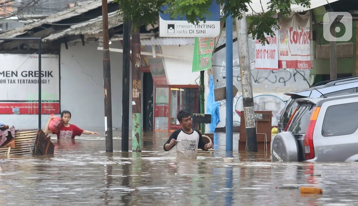 Warga melintasi banjir  yang merendam jalan Raya KH Hasyim Ashari, Ciledug ,Tangerang, Rabu (1/1/2020). Banjir setinggi dada orang dewasa membuat jalur penghubung Tangerang ke Jakarta tersebut terputus tidak dapat dilintasi. (Liputan6.com/Angga Yuniar)