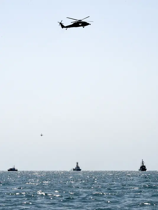 Pesawat tak berawak AL AS Martin UAV, helikopter Seahawk SH-60S, kapal Penjaga Pantai Bahrain Deraa 13 (kiri), Penjaga Pantai AS Maui (tengah), dan AL Kerajaan Bahrain Abdulrahman Al Fadhel (kanan) saat latihan bersama di perairan Teluk, 26 Oktober 2021. (MAZEN MAHDI/AFP)
