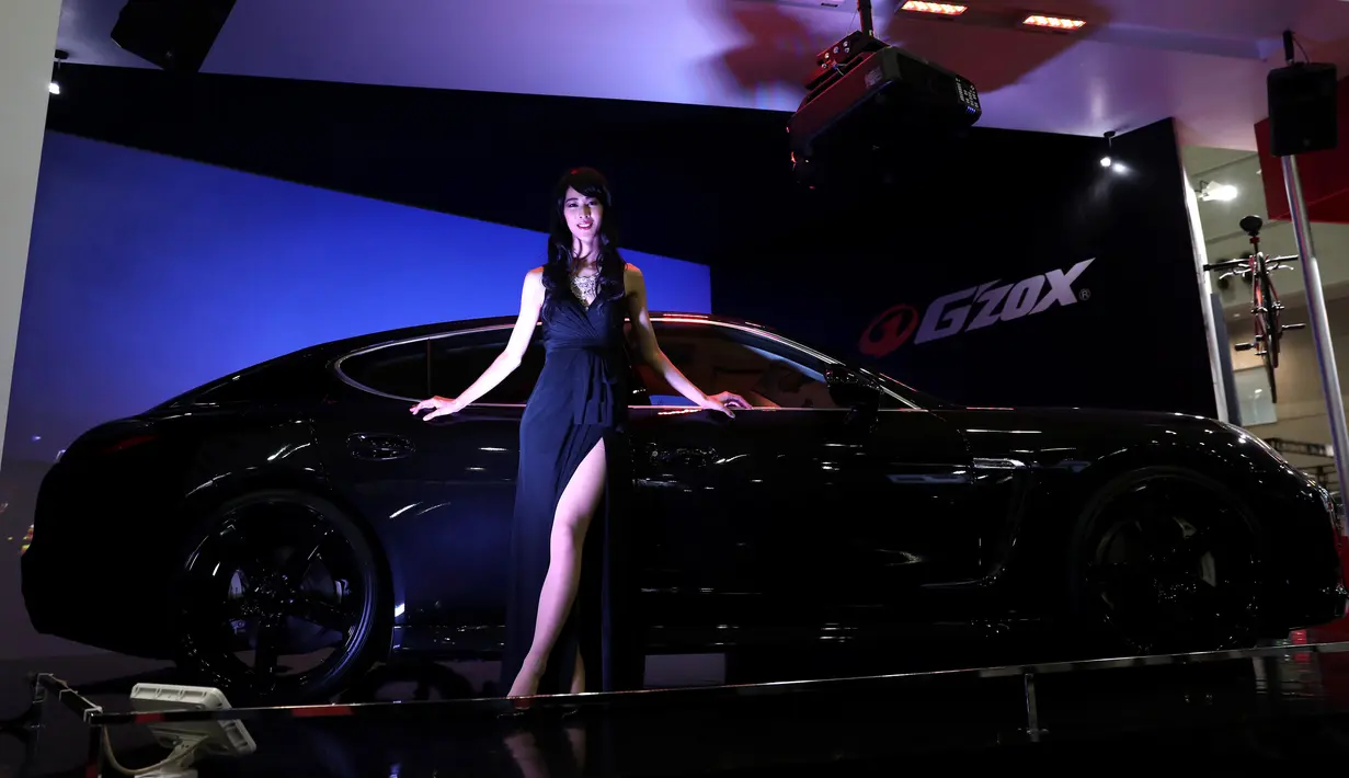 Seorang model berpose di dekat Porsche saat Tokyo Auto Salon 2017 di Chiba, Jepang, Jumat (13/1). Tokyo Auto Salon 2017 menghadirkan berbagai produk otomotif keluaran terbaru serta mobil-mobil kustom teranyar. (AFP PHOTO/ BEHROUZ MEHRI)