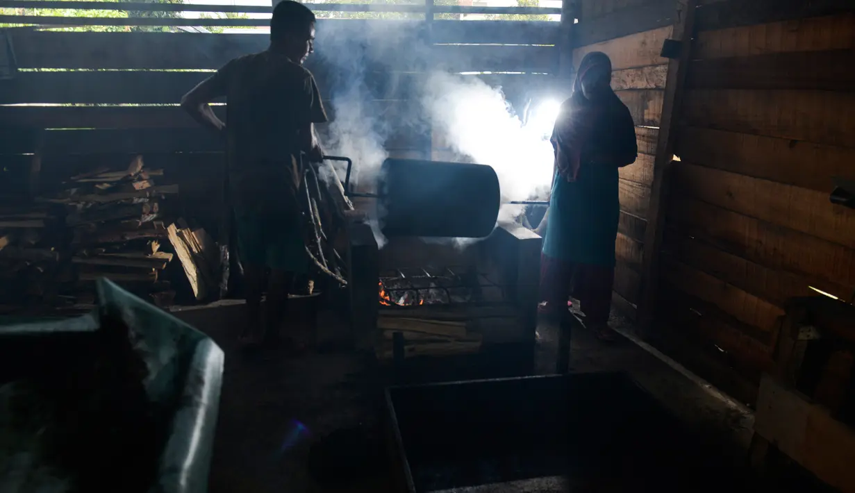 Perajin memanggang biji kopi robusta menggunakan alat tradisional di salah satu industri rumah tangga di Ulee Kareng, Aceh, Rabu (20/11/2019). Kopi yang diolah secara tradisional itu dijual dengan kisaran harga beragam tergantung kualitas. (CHAIDEER MAHYUDDIN/AFP)