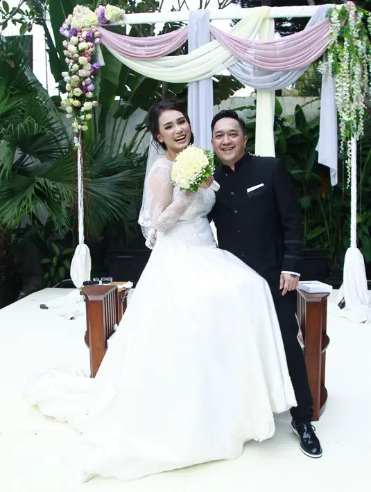 Pasangan pengantin baru ini menebarkan senyum penuh kebahagiaan setelah keduanya akhirnya resmi menikah. Feby Febiola tampak cantik dengan gaun pengantin putih, Franky pun tampak  gagah dengan busana pengantin pria. (Galih W. Satria/Bintang.com)
