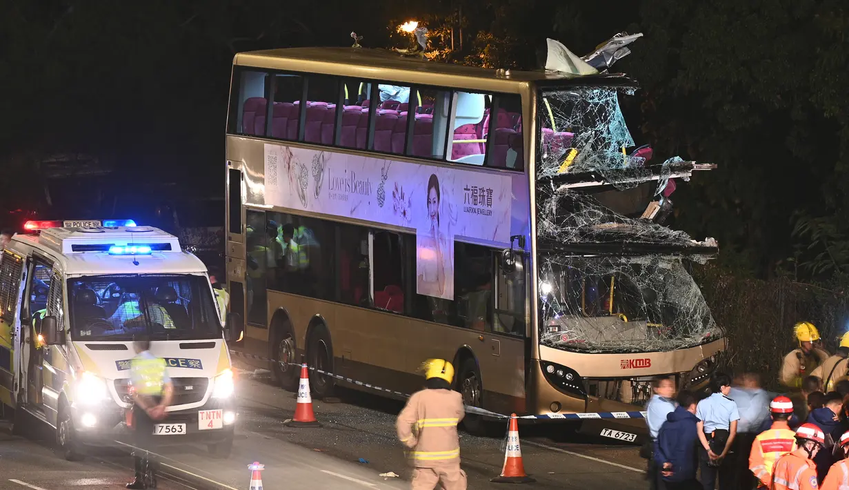 Petugas pemadam kebakaran, petugas medis, dan polisi berkumpul dekat bus tingkat dua yang menabrak pohon di Kwu Tung, Hong Kong, Rabu (18/12/2019). Kecelakaan tersebut mengakibatkan enam orang tewas dan belasan lainnya luka-luka. (Philip FONG/AFP)