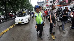 Petugas mengukur jarak terjadinya kecelakaan tabrakan Outlander saat olah TKP di Arteri Pondok Indah, Jakarta, Kamis (22/1/2015). (Liputan6.com/Miftahul Hayat)