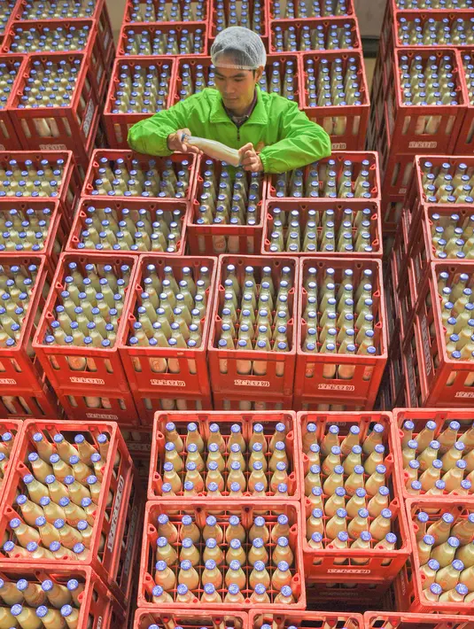 Pekerja memeriksa botol-botol susu kedelai di sebuah pabrik di Nanning, Guangxi, China, Selasa (12/3). Pabrikan asal China menghadapi tekanan penjualan di dalam dan luar negeri. (STR/AFP)
