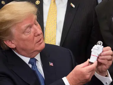 Presiden AS, Donald Trump memegang mainan Astronot setelah menandatangani sebuah kebijakan untuk mengirim astronot Amerika kembali ke bulan dan Mars di Ruang Roosevelt Gedung Putih di Washington (11/12). (AFP/Saul Loeb)