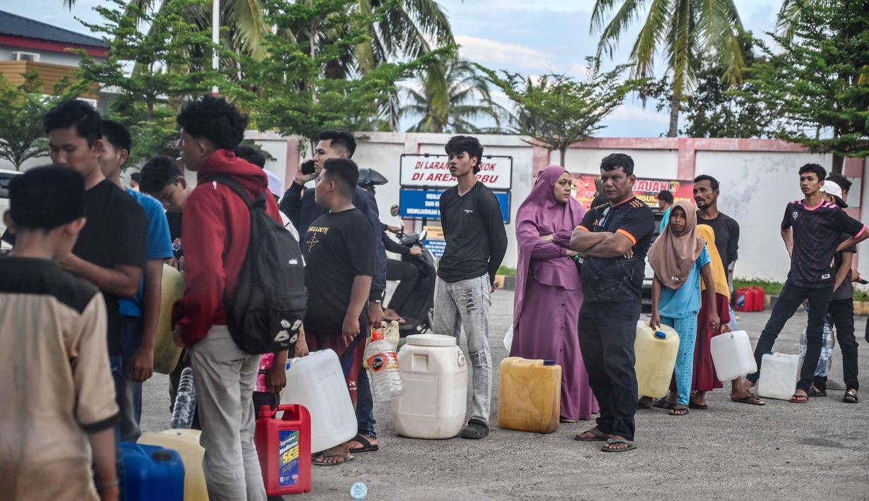 Masyarakat tidak hanya membutuhkan BBM untuk kendaraan, tetapi juga untuk mengoperasikan genset (generator set) di rumah. Tampak dalam foto, warga terdampak banjir mengantre untuk mendapatkan bahan bakar di sebuah Stasiun Pengisian Bahan Bakar Umum (SPBU) di Samahani, Provinsi Aceh, pada 2 Desember 2025. (CHAIDEER MAHYUDDIN/AFP)