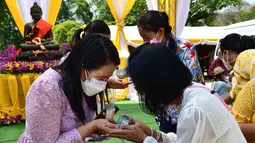 Umat Buddha menuangkan air menurut tradisi, untuk mencegah penyebaran virus corona Covid-19, saat mereka merayakan Tahun Baru Buddha, yang secara lokal dikenal sebagai Songkran, di kuil Prachapirom di Narathiwat (12/4/2022). (AFP/Madaree Tohlala)