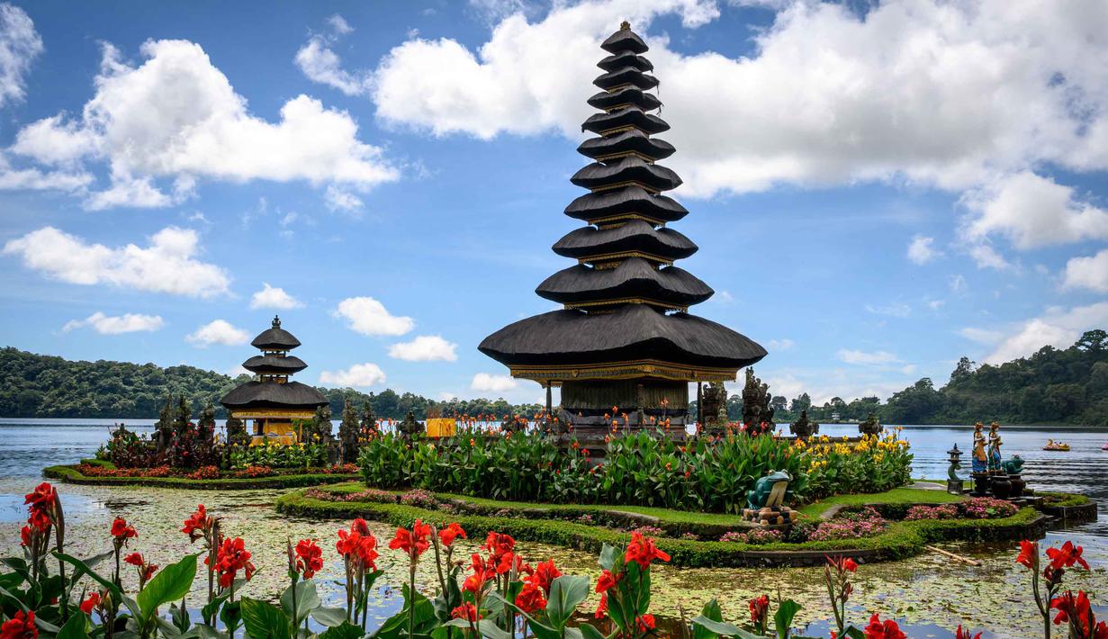 Ketenangan air Danau Beratan menciptakan refleksi yang indah dari pura dan pegunungan di permukaannya. Tampak dalam foto, sejumlah pemuda bersiap mengikuti prosesi keagamaan di Pura Ulun Danu Beratan, sebuah pura Hindu di Danau Beratan dekat Bedugul, Bali, pada Jumat 7 November 2025. (Mladen ANTONOV/AFP)