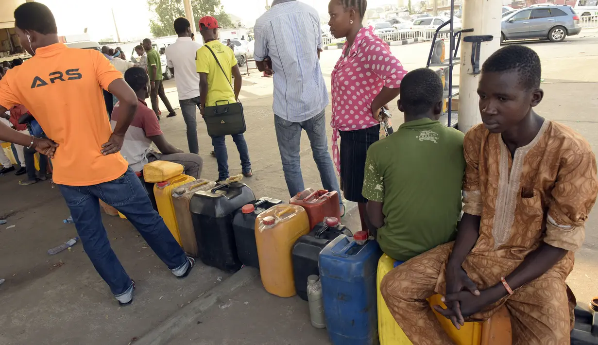 Warga Nigeria duduk di atas jerigen saat antre mengisi bahan bakar di sebuah SPBU di Lagos, Selasa (1/12). Krisis bahan bakar yang telah melanda Nigeria dalam beberapa bulan terakhir menyebabkan antrean panjang di SPBU. (AFP PHOTO/PIUS Utomi EKPEI)