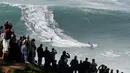 Penonton menyaksikan peselancar unjuk kebolehan dalam menaklukkan ombak besar di Praia do Norte atau Pantai Utara, Nazare, Portugal, Rabu (20/11/2019). Ombak di perairan ini disebut-sebut paling menantang dan paling berbahaya di dunia. (AP Photo/Armando Franca)