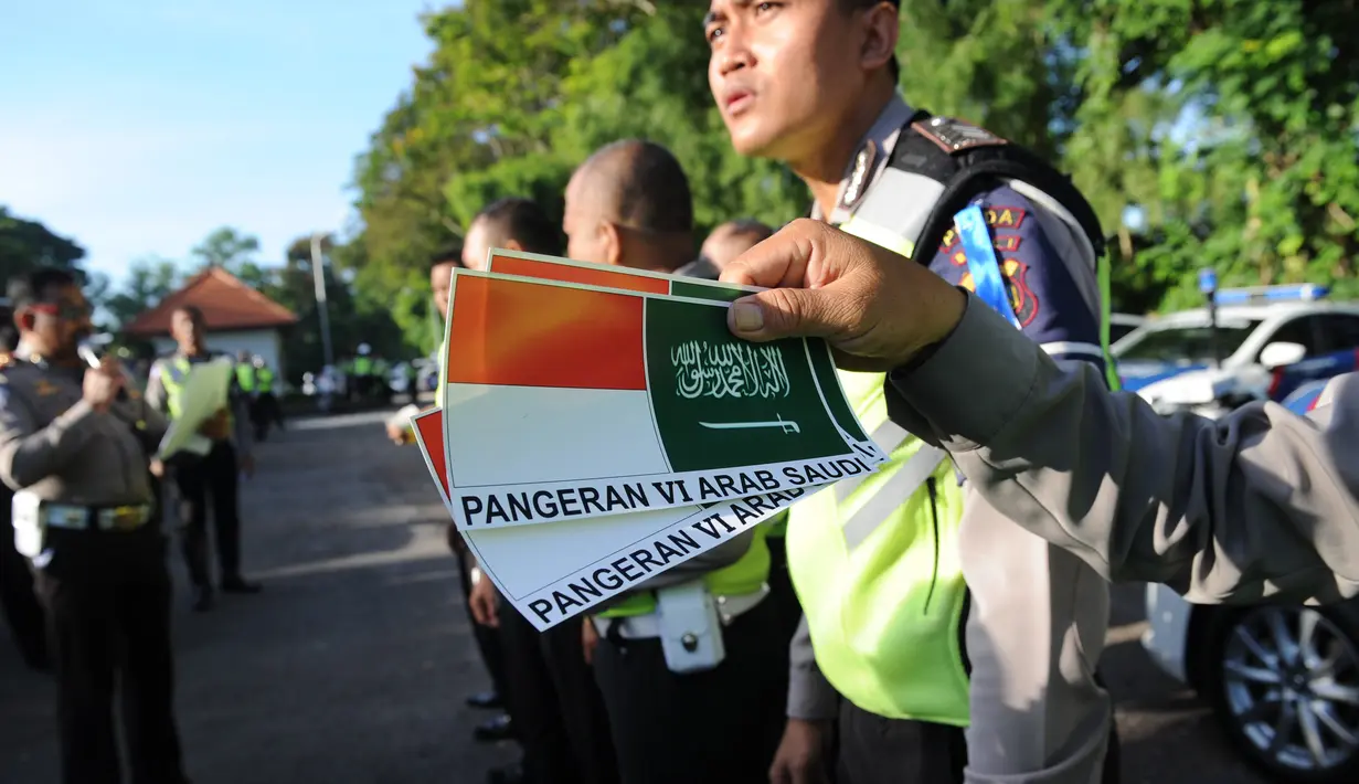 Petugas polisi menunjukkan stiker bergambar bendera Indonesia dan Arab Saudi selama persiapan menyambut kedatangan Raja Salman bin Abdulaziz di Nusa Dua, Bali (2/3). (AFP Photo / Sonny Tumbelaka)