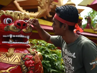 Seorang pekerja mengecat patung di depan kuil Cina di Denpasar, Bali, Senin (23/1). Pengecatan ini dilakukan dalam rangka menyambut pergantian tahun baru Imlek 2568. (AFP PHOTO / SONNY Tumbelaka)