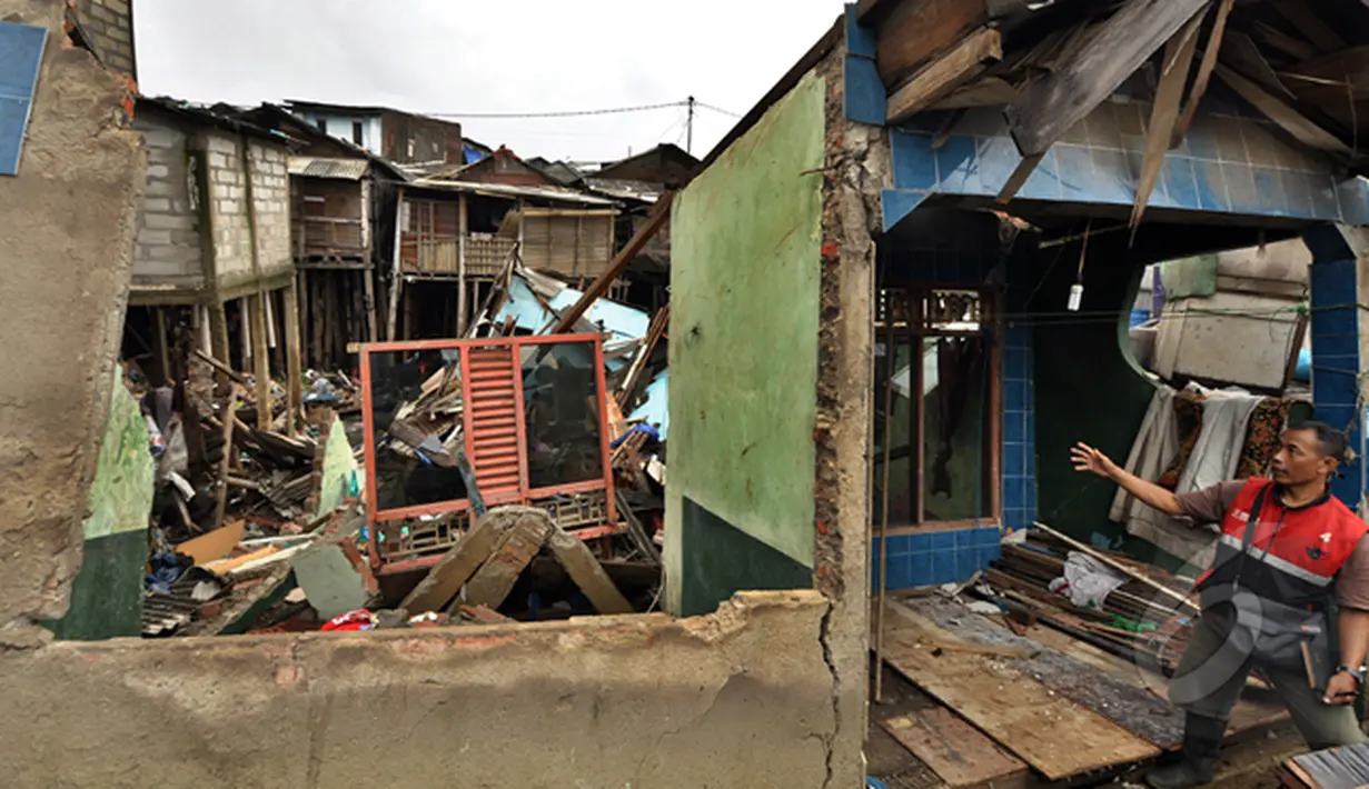 Seorang laki-laki menunjukan rumah yang rubuh dikawasan muara baru, Jakarta, Jumat (13/2/2015).  Sebanyak 33 rumah di muara baru Jakarta Utara mengalami kemiringan parah dan 2 buah rumah ambruk akibat banjir. (Liputan6.com/Faizal Fanani)