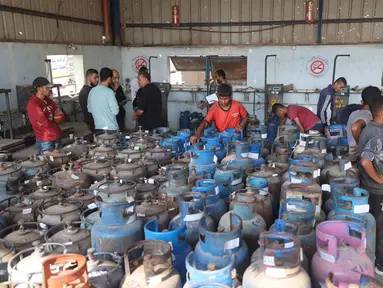 Pekerja Palestina mengisi tabung gas di stasiun pengisian resmi di kamp pengungsi Nuseirat, di bagian tengah Jalur Gaza, pada Senin 10 November 2025. Meski dalam jumlah terbatas, pasokan bahan bakar gas untuk memasak mulai didistribusikan ke warga Gaza. (Eyad Baba/AFP)