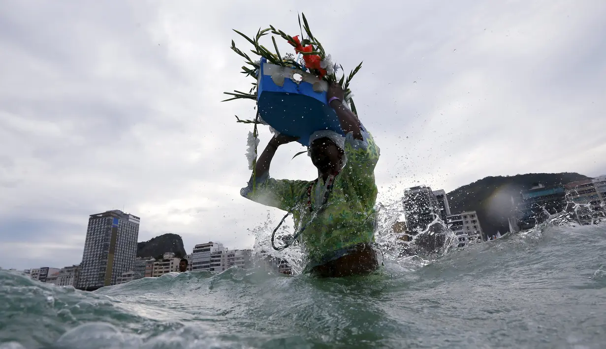Pengikut agama Afro - Brazilian Umbanda membawa persembahan untuk Iemanja, di Pantai Copacabana di Rio de Janeiro, Brasil, (29/12). Acara ini dinamakan Worshippers yaitu pemberian kepada dewi laut dalam menyambut tahun baru. (REUTERS/Ricardo Moraes) 	