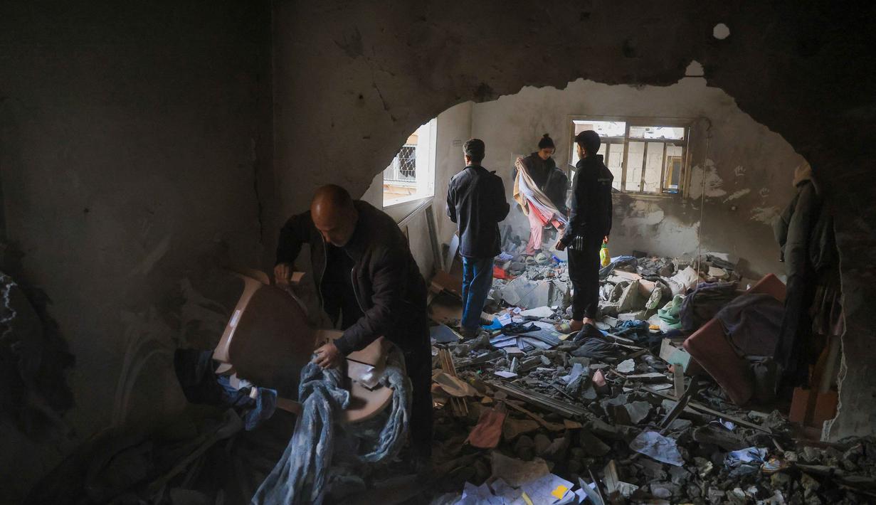 Pemerintah Palestina di Gaza melaporkan Israel melakukan sedikitnya 1.244 pelanggaran selama fase pertama gencatan senjata yang mulai berlaku pada 10 Oktober 2025. Tampak dalam foto, warga Palestina menyelamatkan barang-barang dari sebuah rumah setelah serangan militer Israel terhadap rumah keluarga al-Houli, di mana empat orang dilaporkan tewas, di sebelah barat Deir al-Balah, di Jalur Gaza tengah pada Jumat 16 Januari 2026. (BASHAR TALEB/AFP)