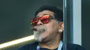 Mantan bintang sepak bola, Diego Maradona merokok saat menyaksikan laga antara Argentina dan Islandia dalam penyisihan Grup D Piala Dunia 2018 di Stadion Spartak, Moskow, Rusia, Sabtu (16/6). (Juan Mabromata/AFP)