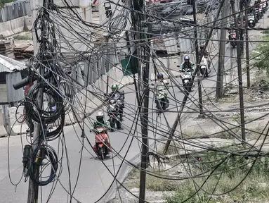 Kendaraan melintas dekat instalasi kabel yang semrawut di Jalan Raya Bekasi, Cakung, Jakarta, Rabu (30/9/2020). Minimnya perawatan pascapembebasan lahan permukiman untuk proyek Tol Dalam Kota membuat jaringan kabel listrik di sepanjang jalan tersebut semrawut. (merdeka.com/Iqbal S. Nugroho)