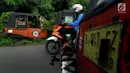 Bangkai bajaj oranye yang sudah tidak dapat digunakan diselimuti tumbuhan liar di kawasan Roxy, Jakarta Barat, Selasa (27/2). (Liputan6.com/JohanTallo)