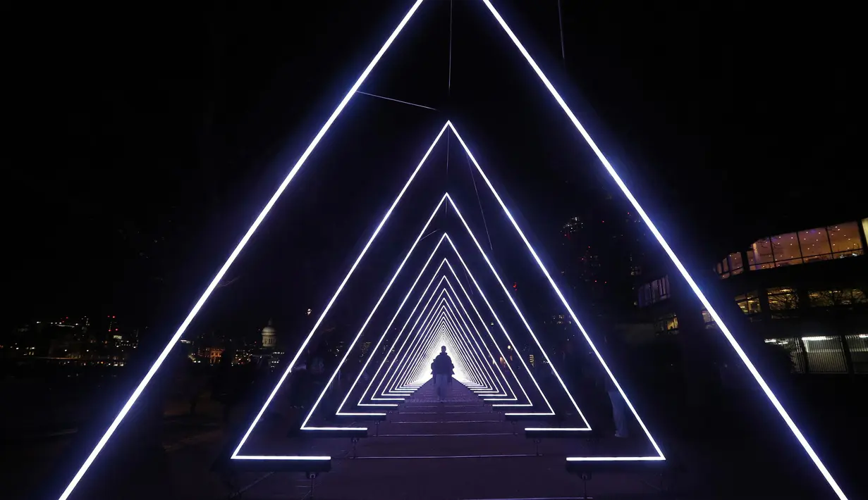 Sejumlah orang berjalan di seni instalasi karya Vertigo selama festival cahaya Lumiere London di Riverside Walkway, South Bank (17/1). Seni instalasi cahaya karya seniman Vertigo ini berjudul The Wave. (Jonathan Brady / PA via AP)
